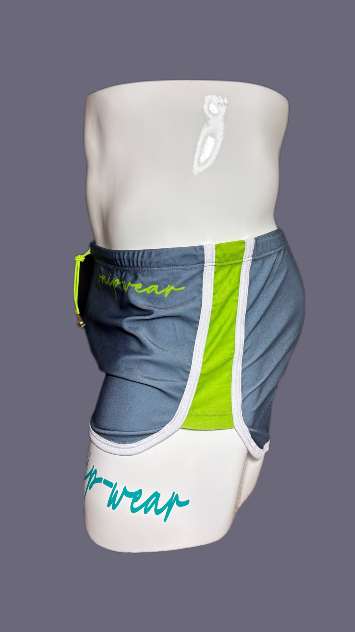Gray shorts with green drawstring and 'onip' branding on a mannequin against a gray background