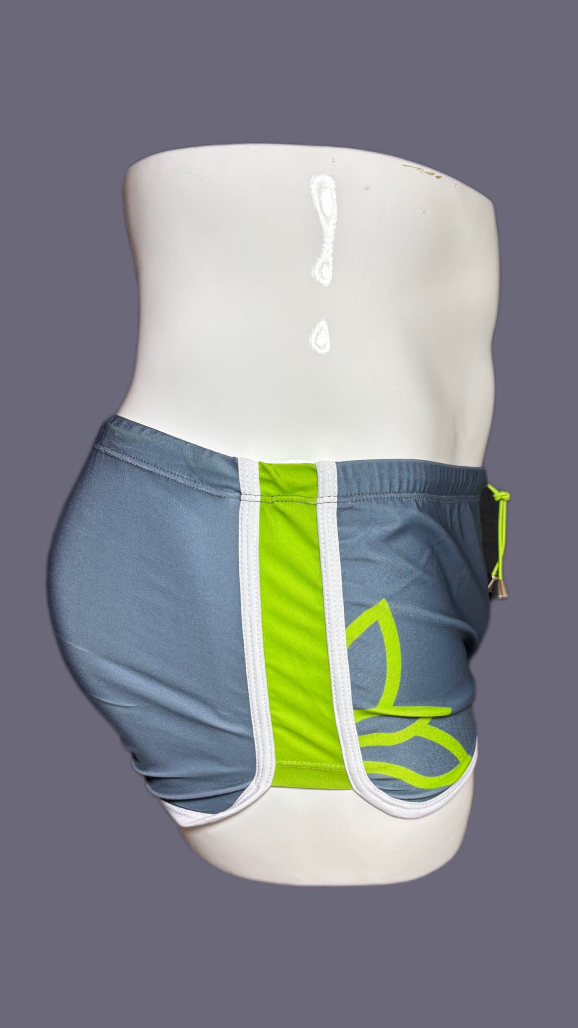Gray shorts with green drawstring and 'onip' branding on a mannequin against a gray background