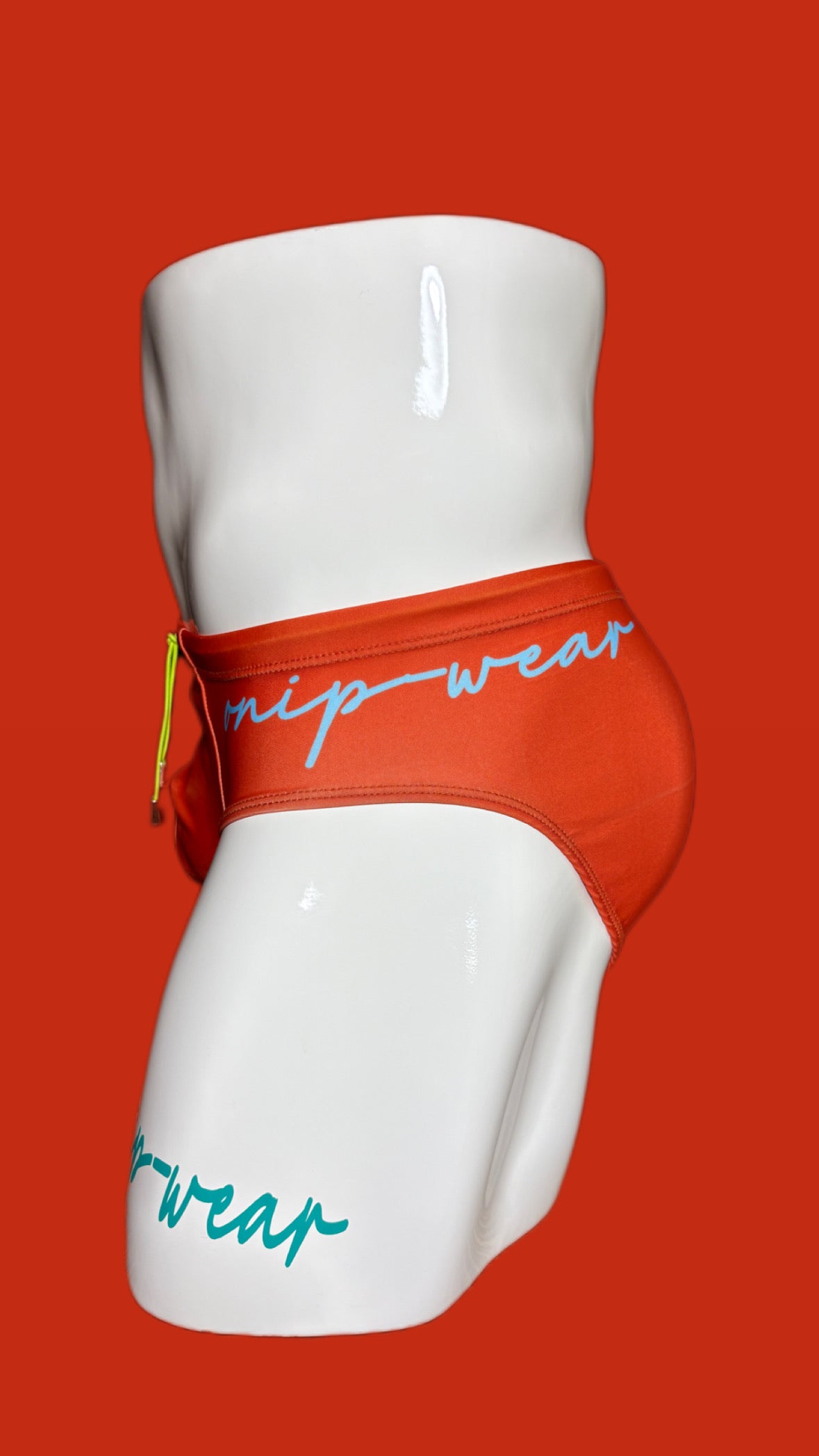 orange swimwear on a white mannequin against a red background