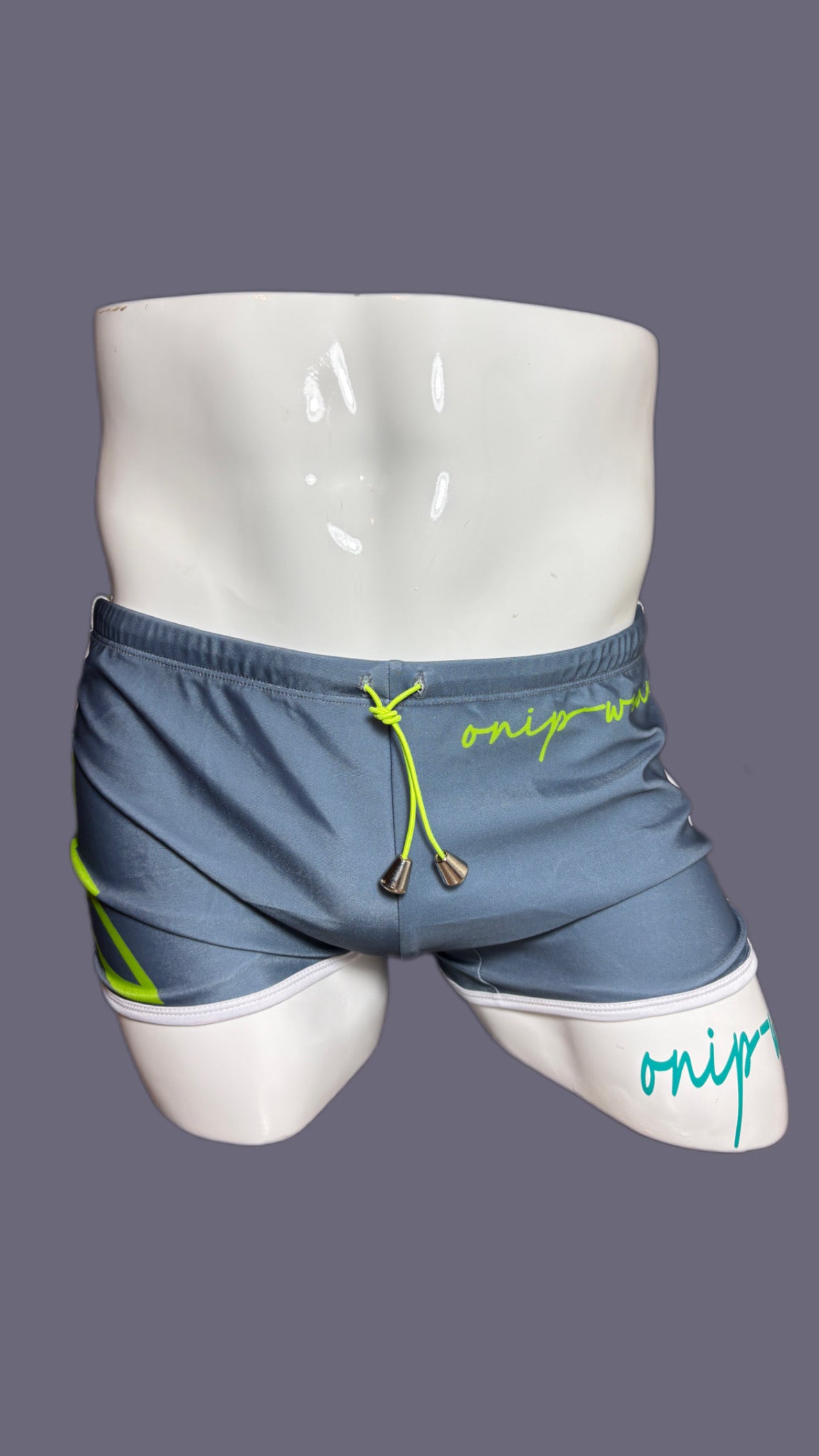 Gray shorts with green drawstring and 'onip' branding on a mannequin against a gray background