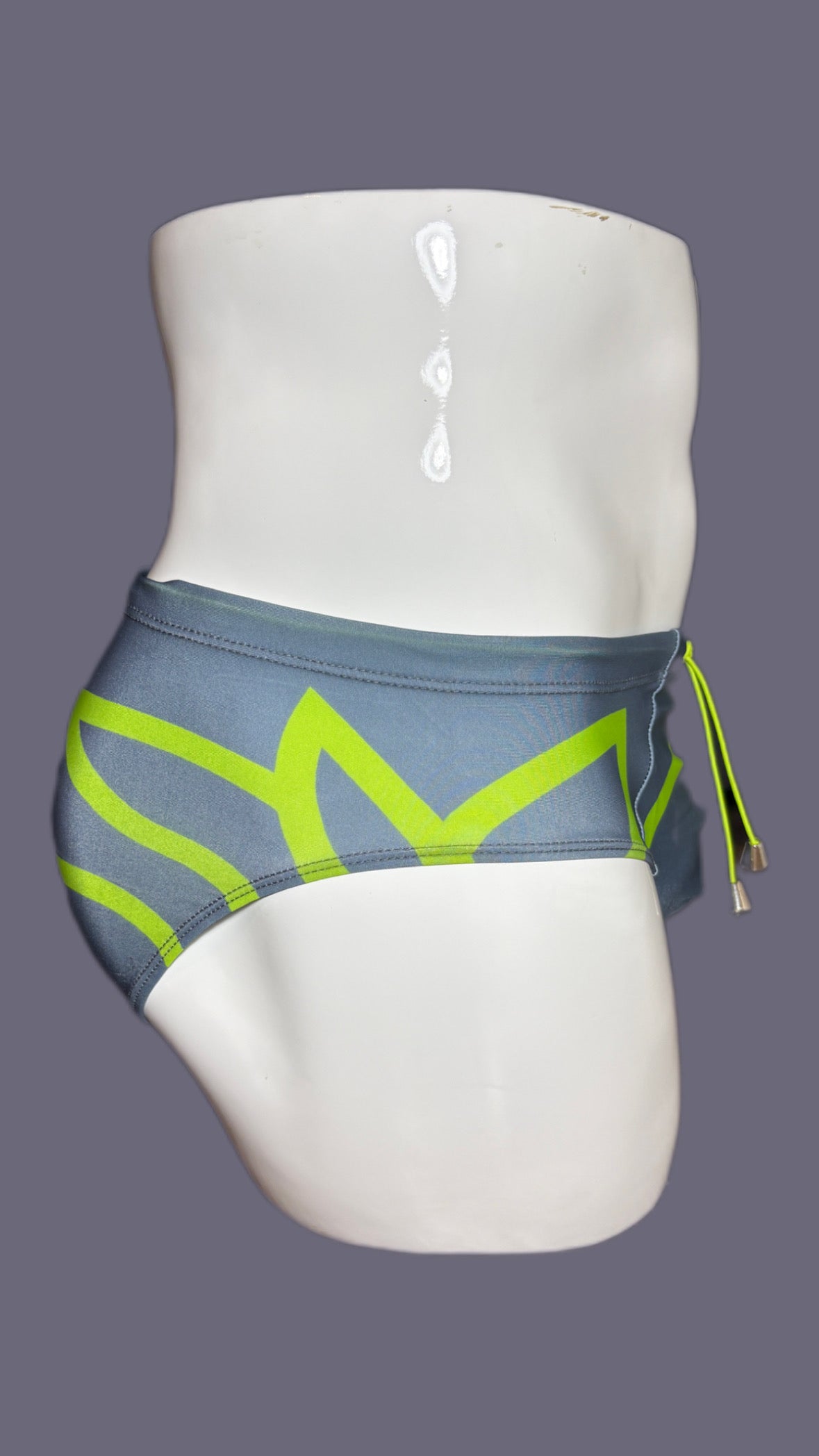 Gray swim briefs with green accents on a mannequin against a gray background