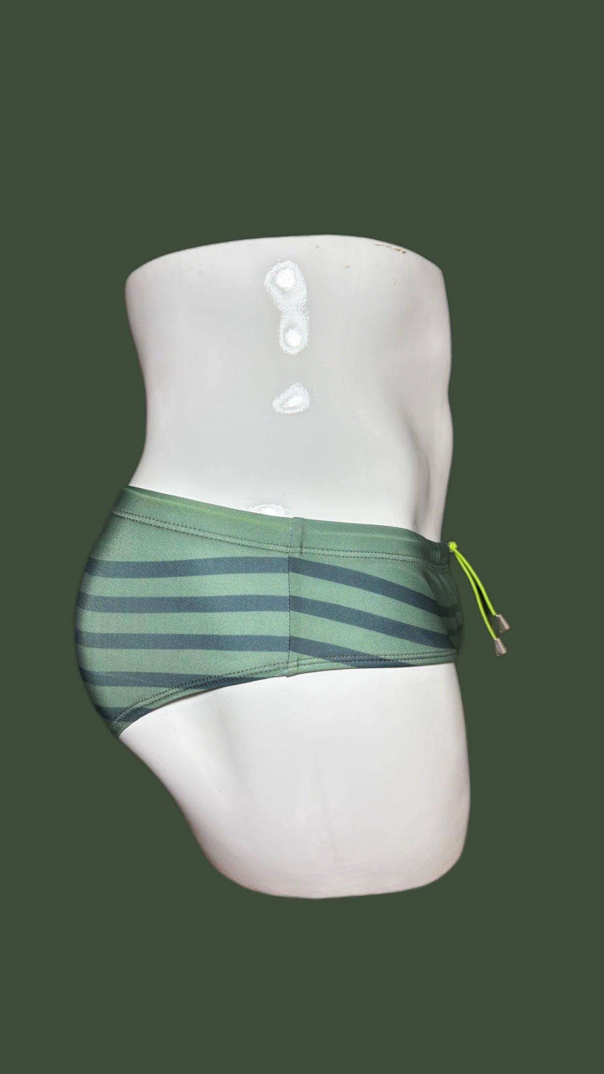 Green striped swimwear on a mannequin against a green background