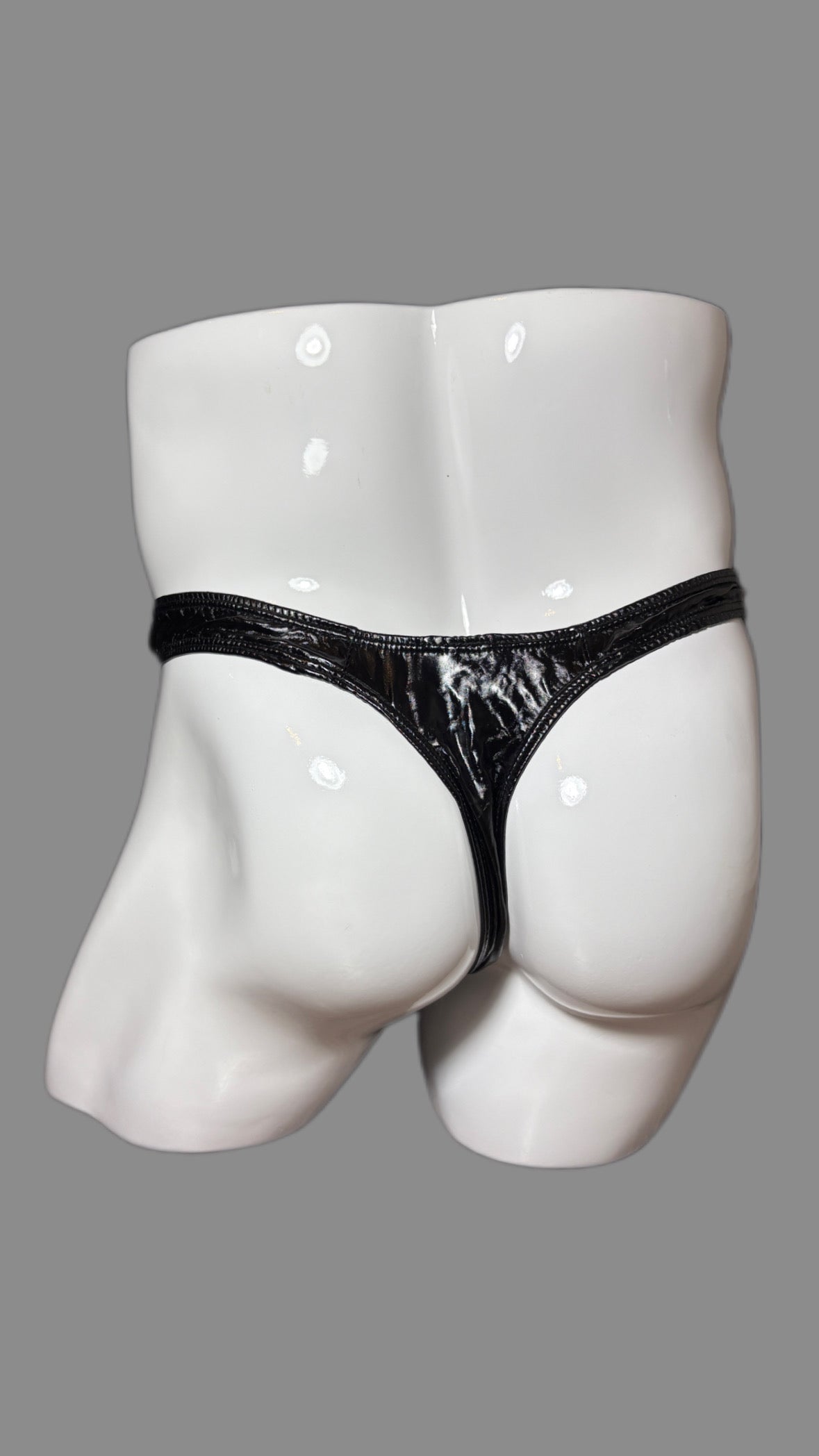 Black thong on a white mannequin against a gray background