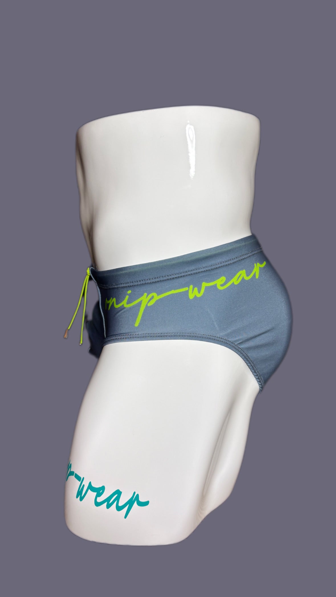 Gray swim briefs with green accents on a mannequin against a gray background